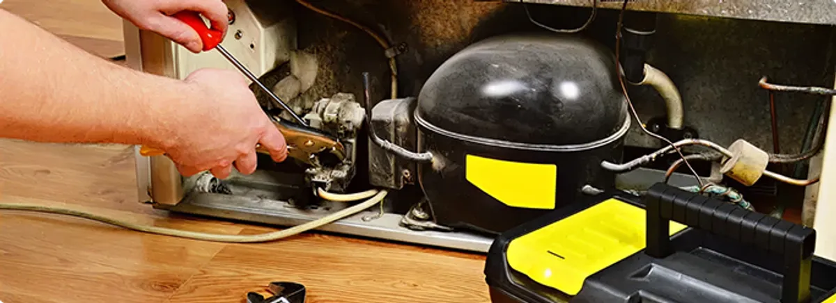 Refrigerator repair technician fixing the compressor and wiring in Phenix City, AL