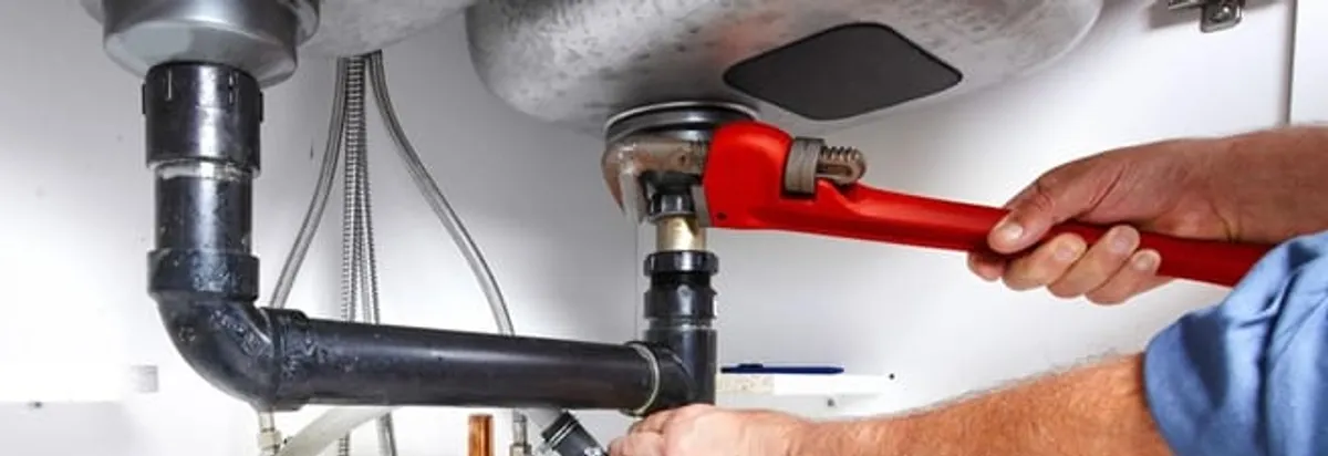 Garbage disposal repair technician tightening the sink drain and disposal connection in Columbus, GA