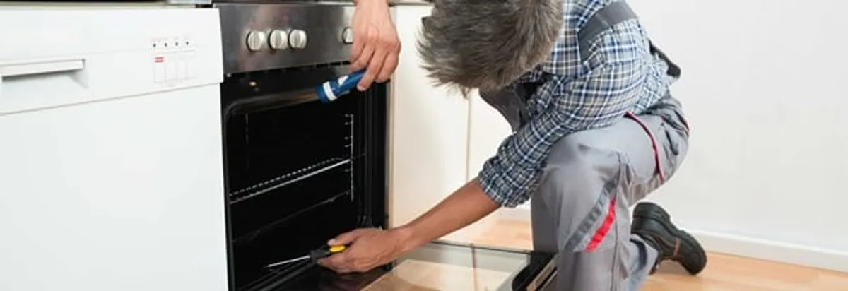 Oven repair technician inspecting and servicing an electric oven in Columbus, GA