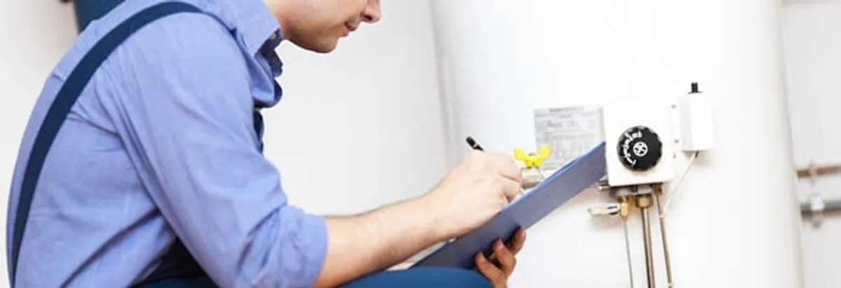 Water heater repair technician inspecting the unit and recording service notes in Columbus, GA